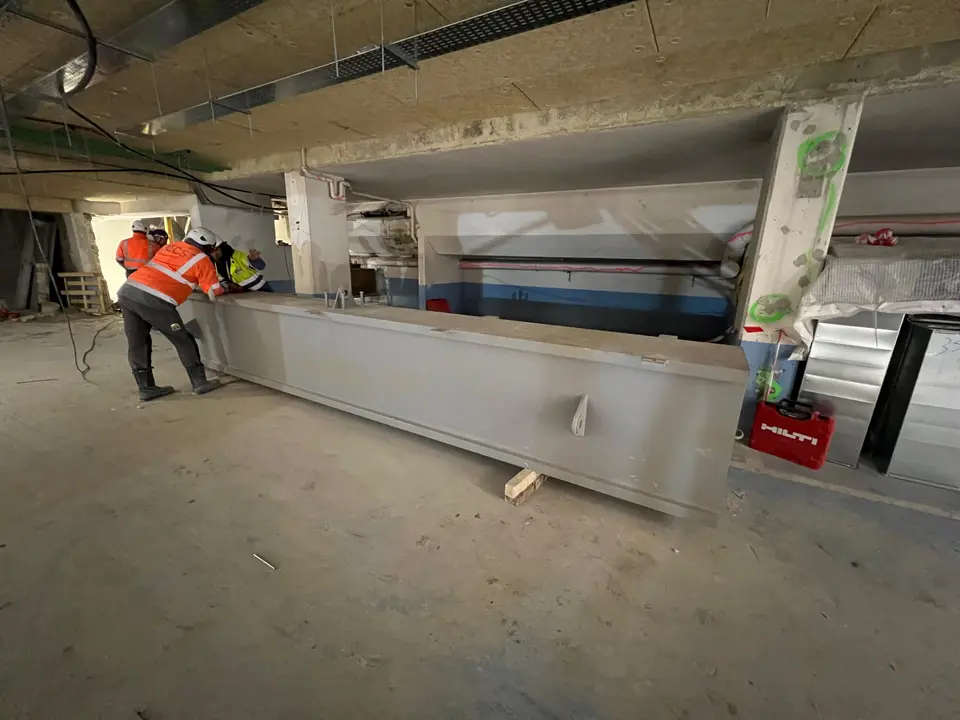 Mise en place d'une poutre métallique de grande longueur en sous-sol technique.