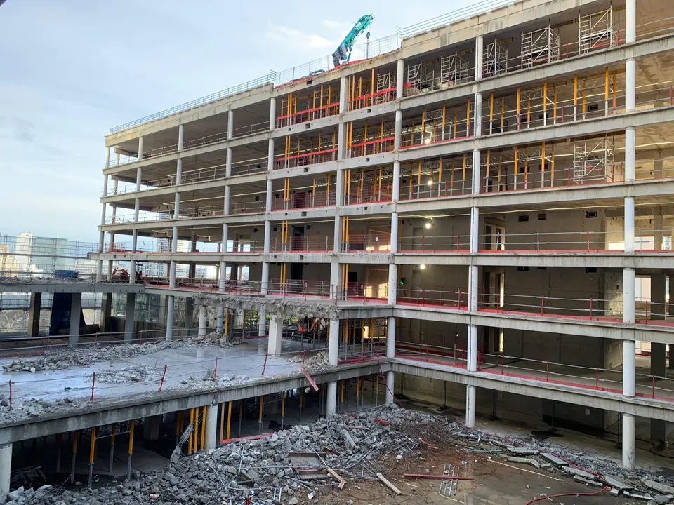 Façade du bâtiment en restructuration — étaiements provisoires (jaune) aux niveaux supérieurs.