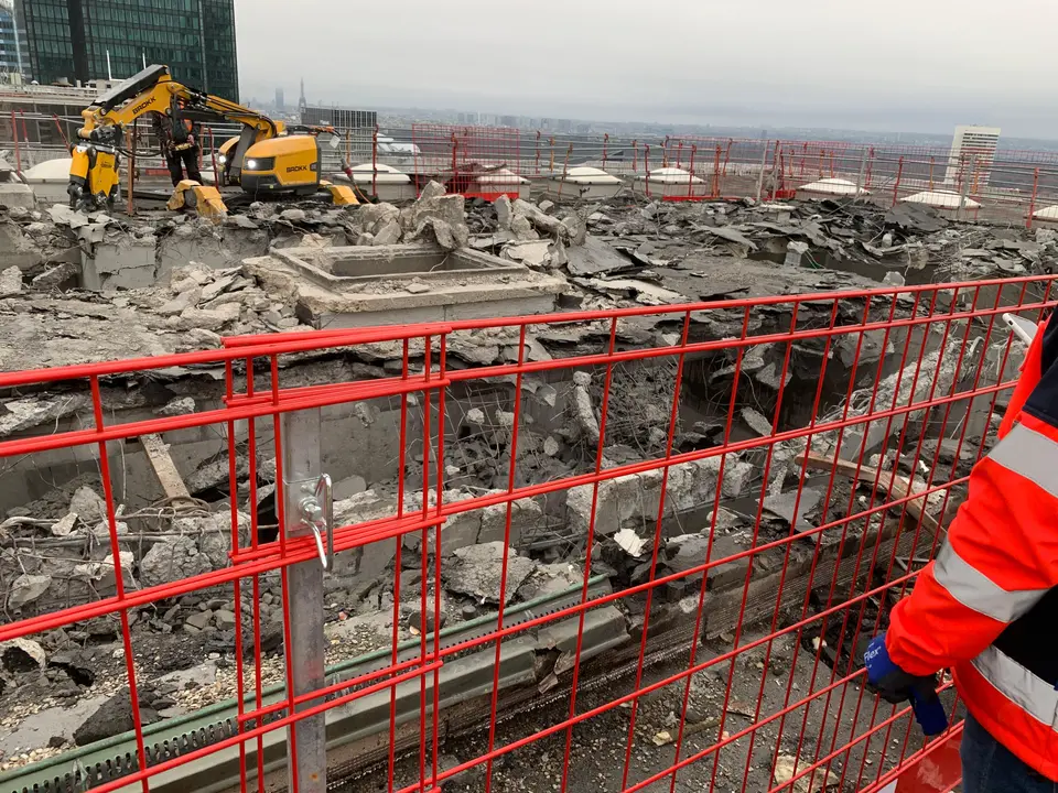 Travaux de démolition en toiture — pelleteuse sur la terrasse haute, La Défense en fond.